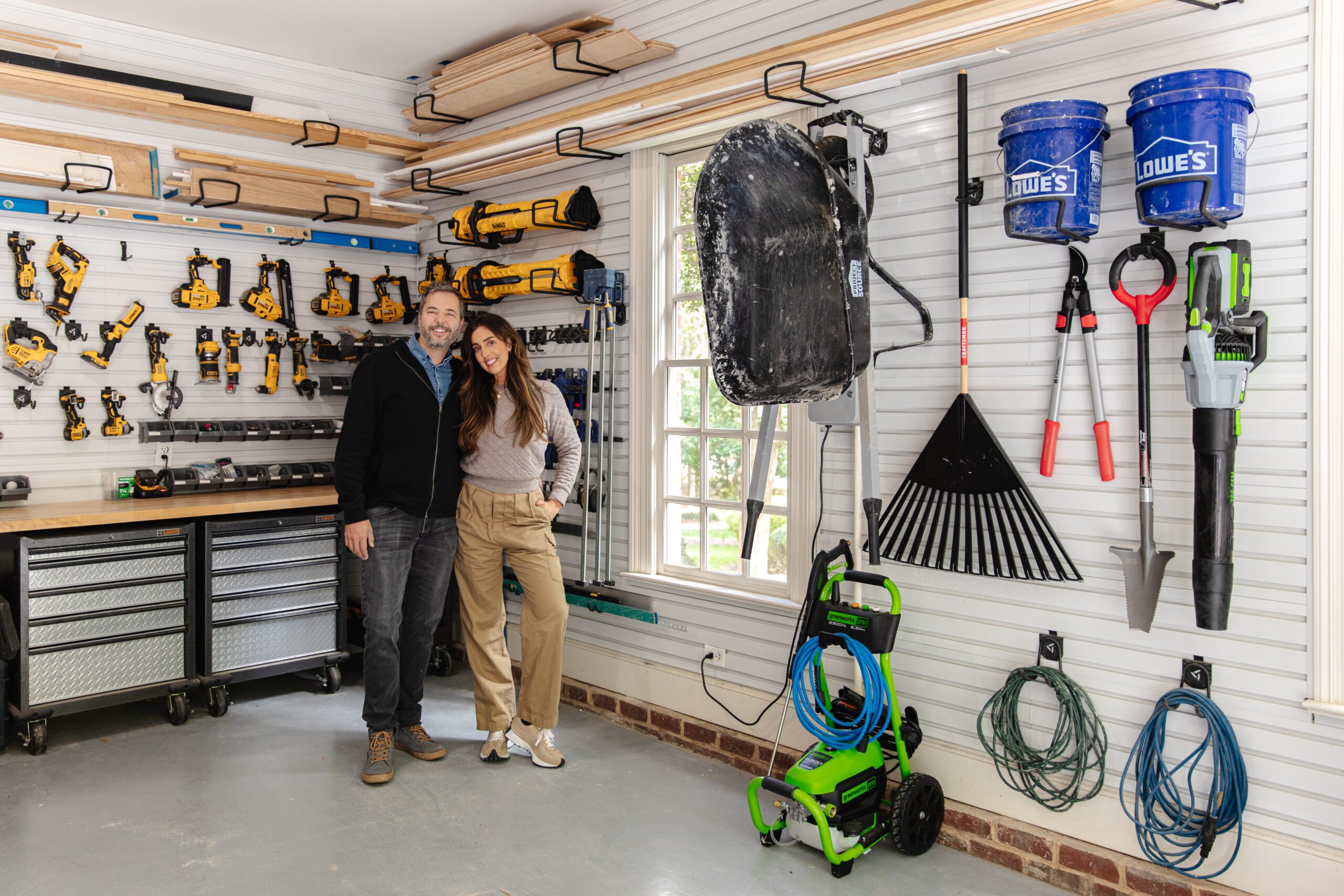 Chris and Julia standing together in a garage with tools hanging on the walls