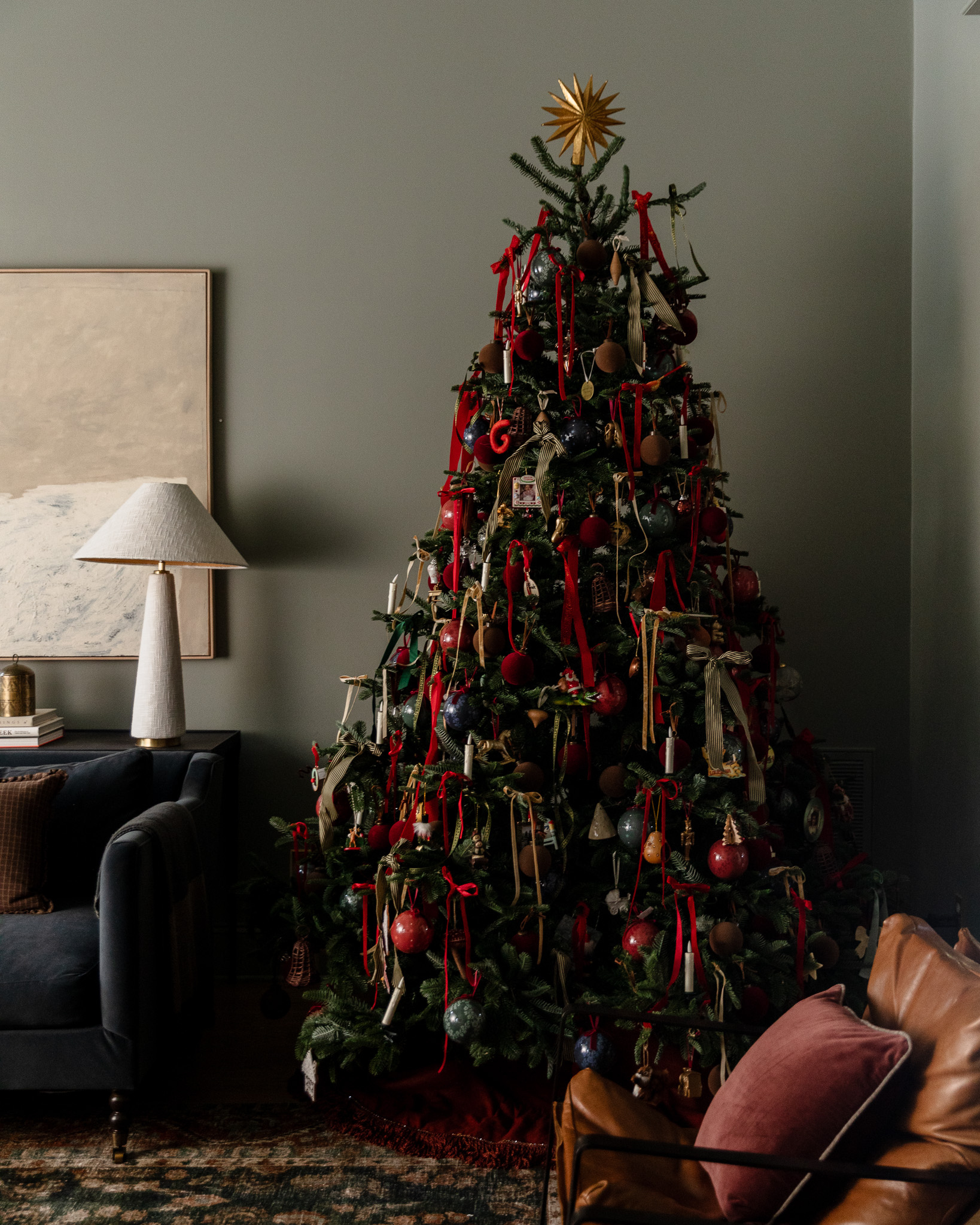 A beautiful traditional Christmas tree draped with velvet ribbons in red, gold, and silver, battery-candles, and a gold sunburst star tree topper