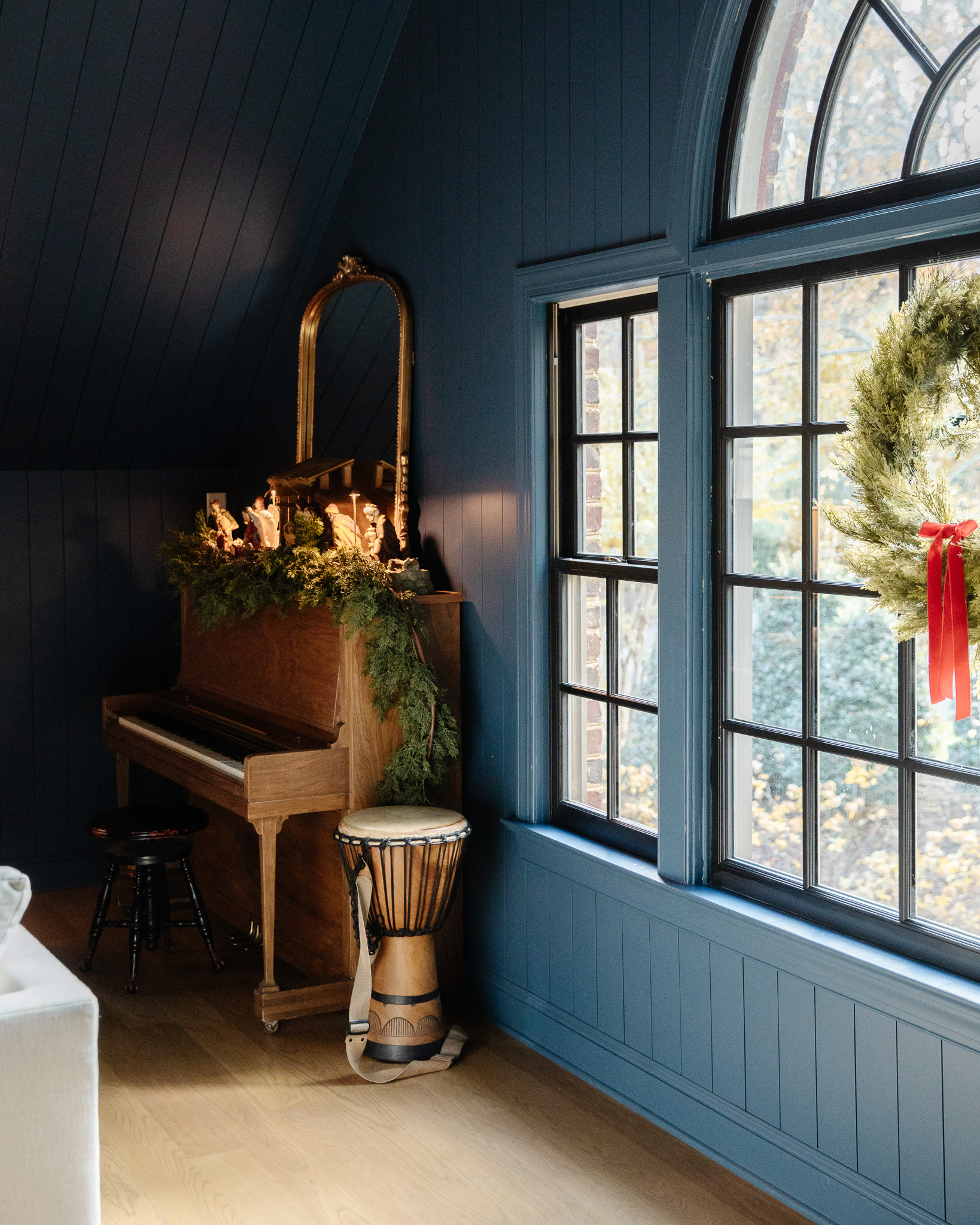 A piano topped with Christmas decorations including a large nativity set and green garland.