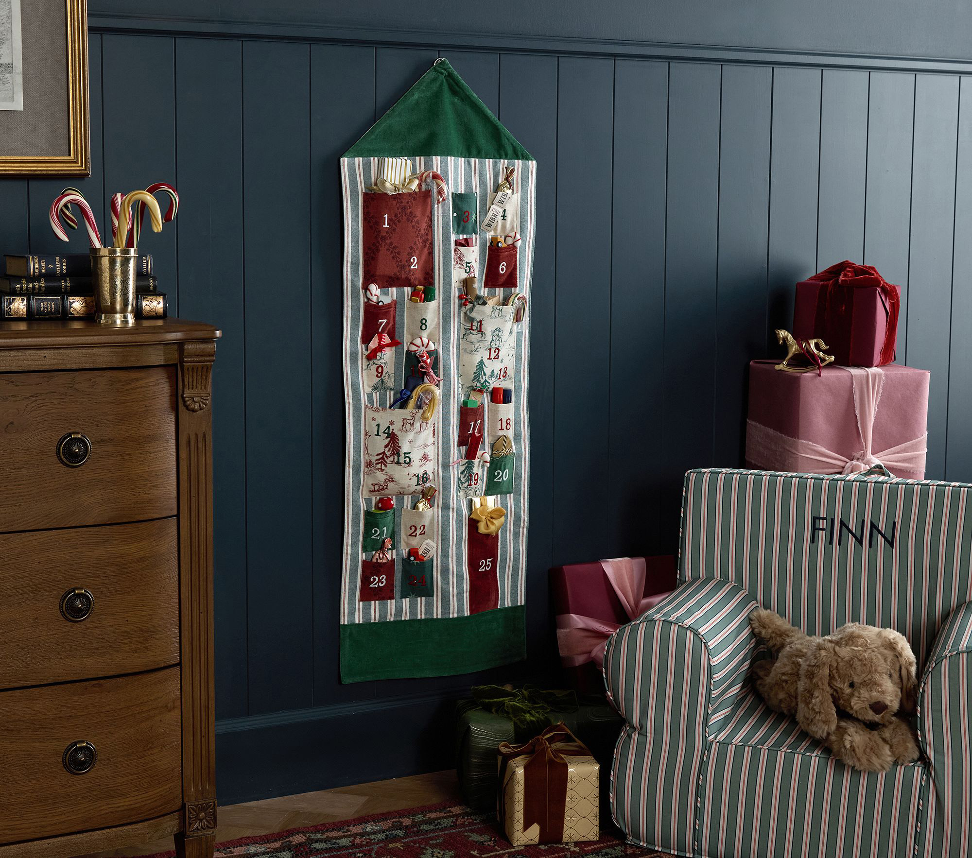 Hanging advent calendar with colorful pockets in dark red, green, and toile filled with presents