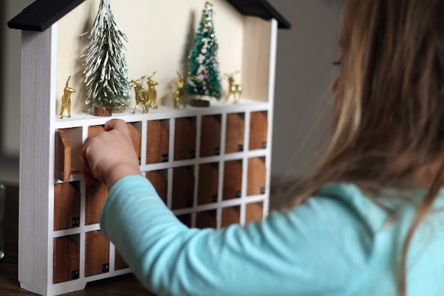 A girl opening a door of a wooden advent calendar