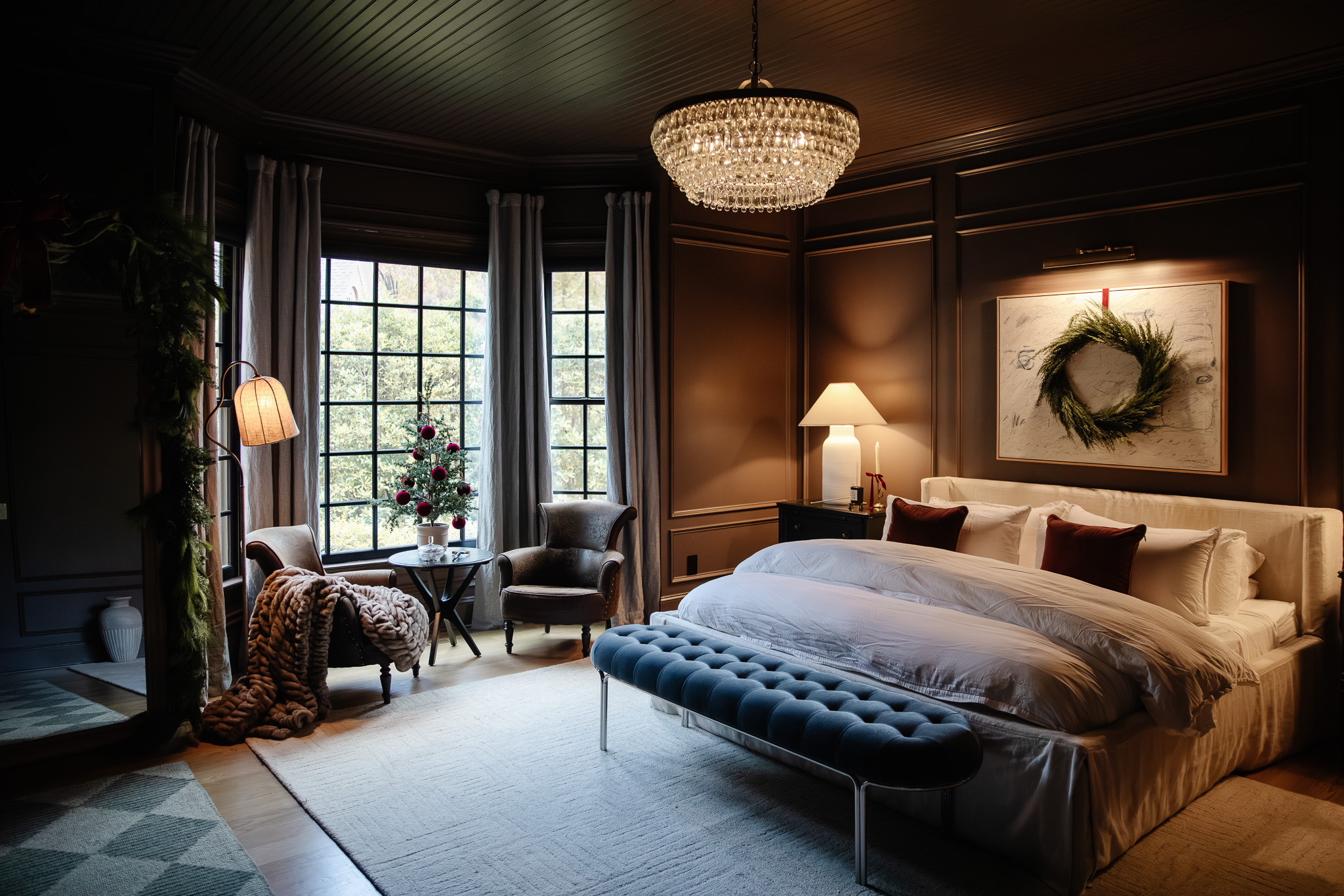 A moody brown bedroom decorated for Christmas with green, burgundy and warm red accents