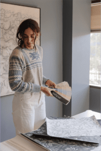 Julia holding a Valspar paint swatch deck while looking at CLJ wallpaper samples