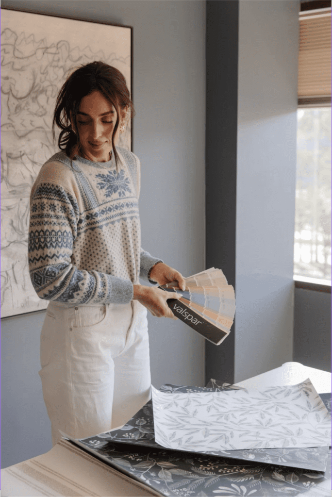 Julia holding a Valspar paint swatch deck while looking at CLJ wallpaper samples