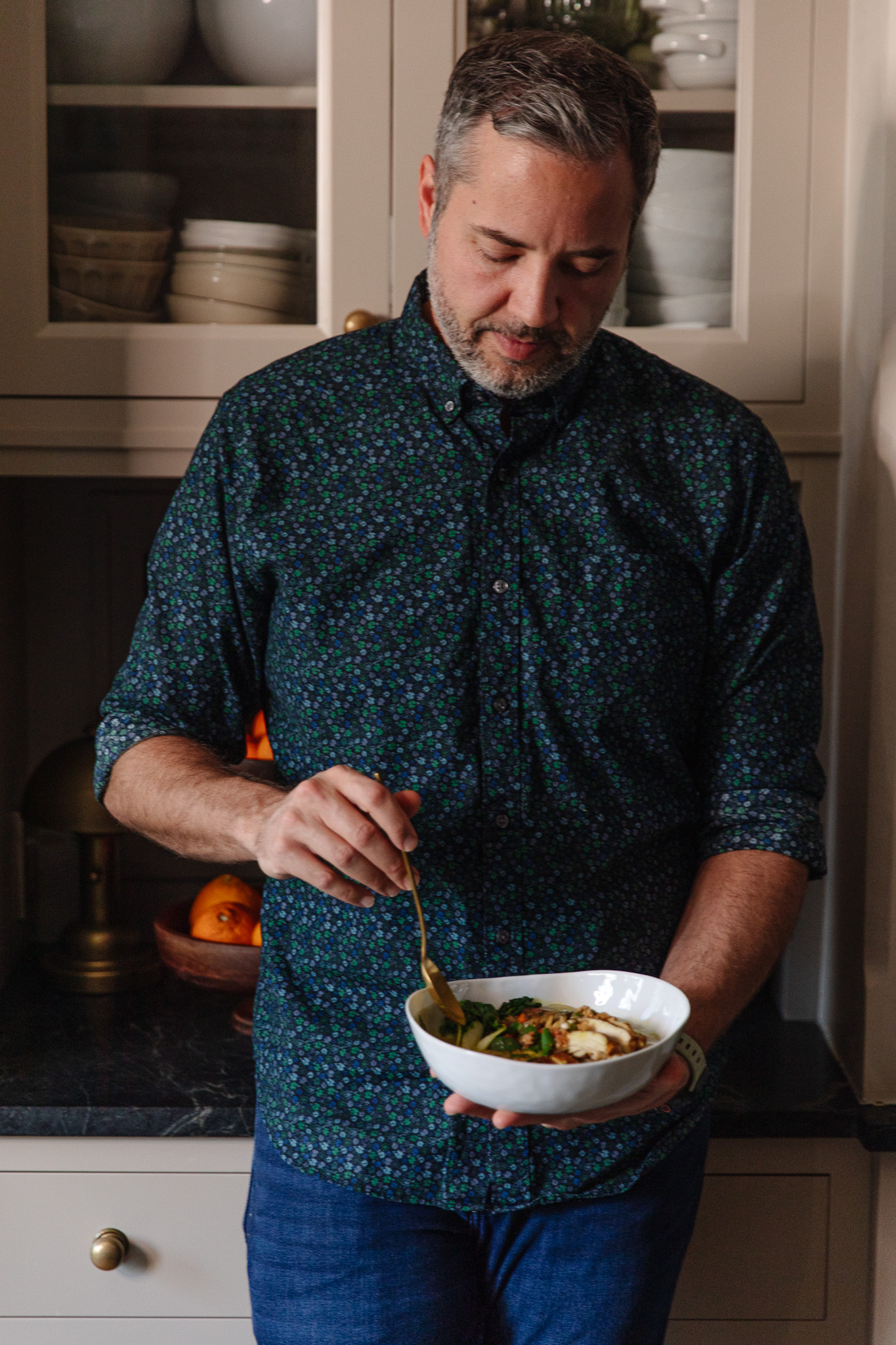 Chris scooping a spoon into a bowl of Singapore Noodles-inspired chicken soup