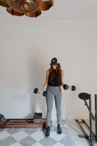Julia lifting weights in the gym in grey leggings and a black top