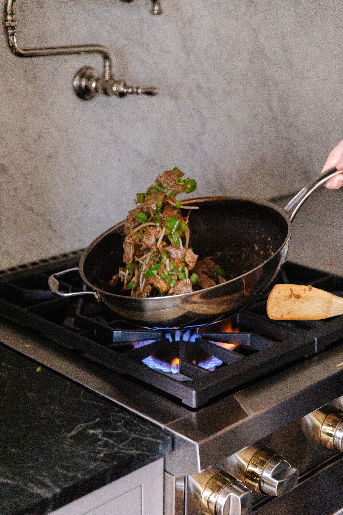 Chris dishing out basil beef stir-fry from a wok to a bowl