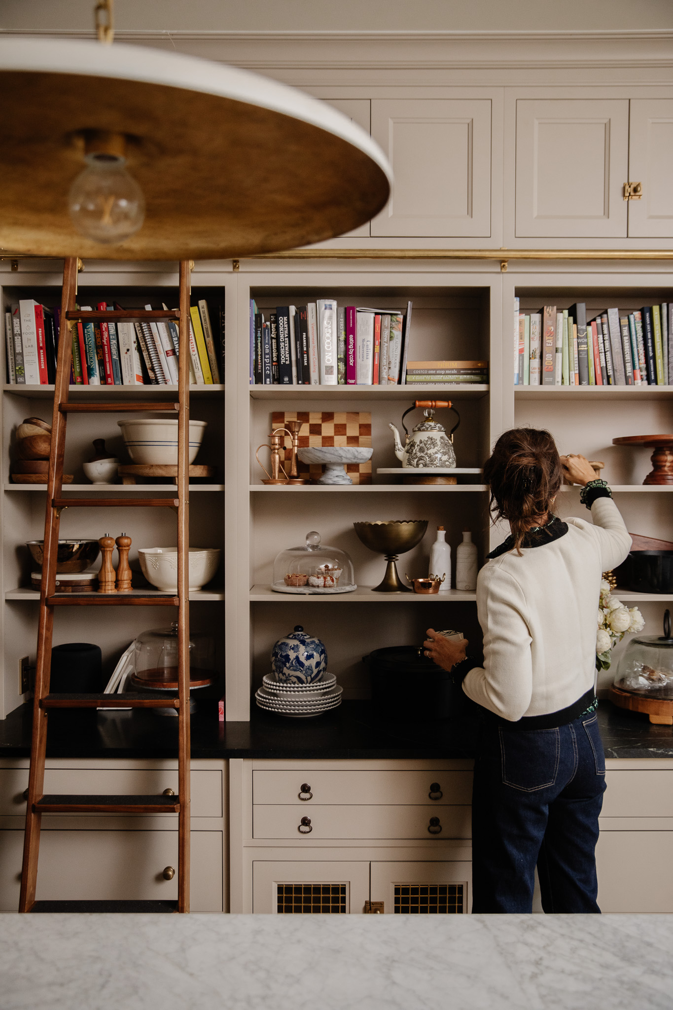 Julia styling a shelf in her kitchen that features an elegant brown floral tea pot