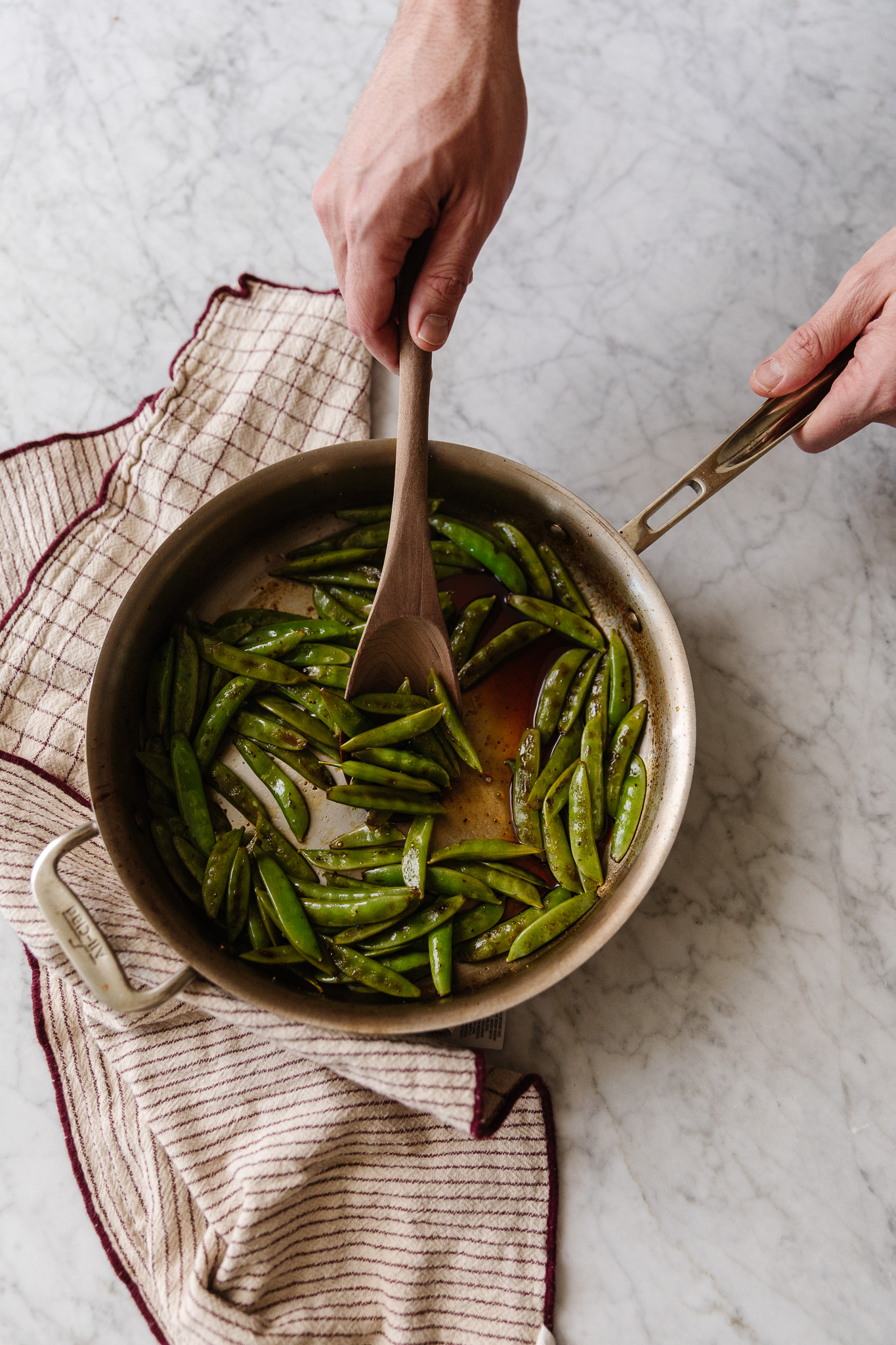 Blistered sugar snap peas with honey in a saute pan