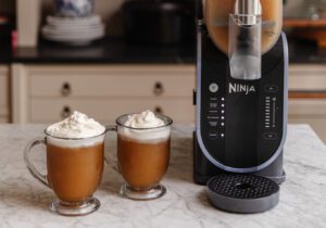 Butterbeer slushies in glass cups next to the Ninja SLUSHi slushie maker