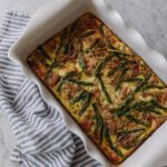 A scalloped casserole dish with ham & asparagus frittata