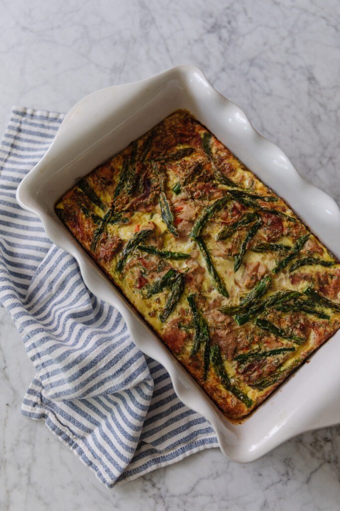 A scalloped casserole dish with ham & asparagus frittata