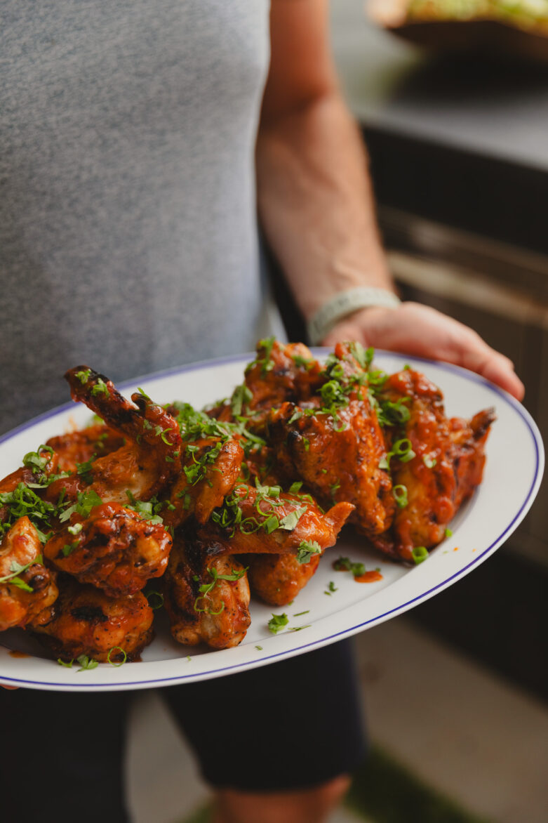Chris holding a platter of grilled wings with pineapple-sriracha glaze
