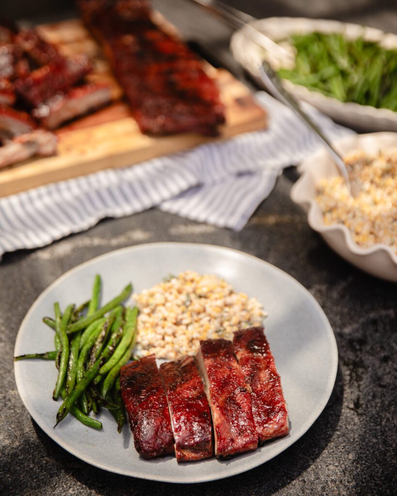 Plate with smoked pork ribs, grilled green beans, and a corn salad