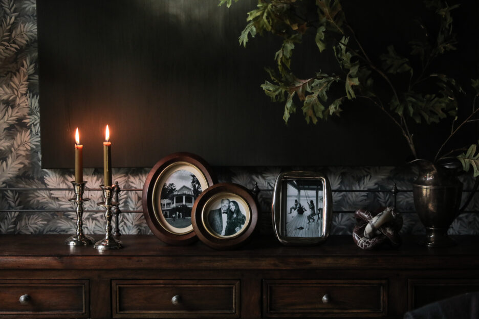 Vintage photo display with candles and decorative objects on a dark wooden sideboard.