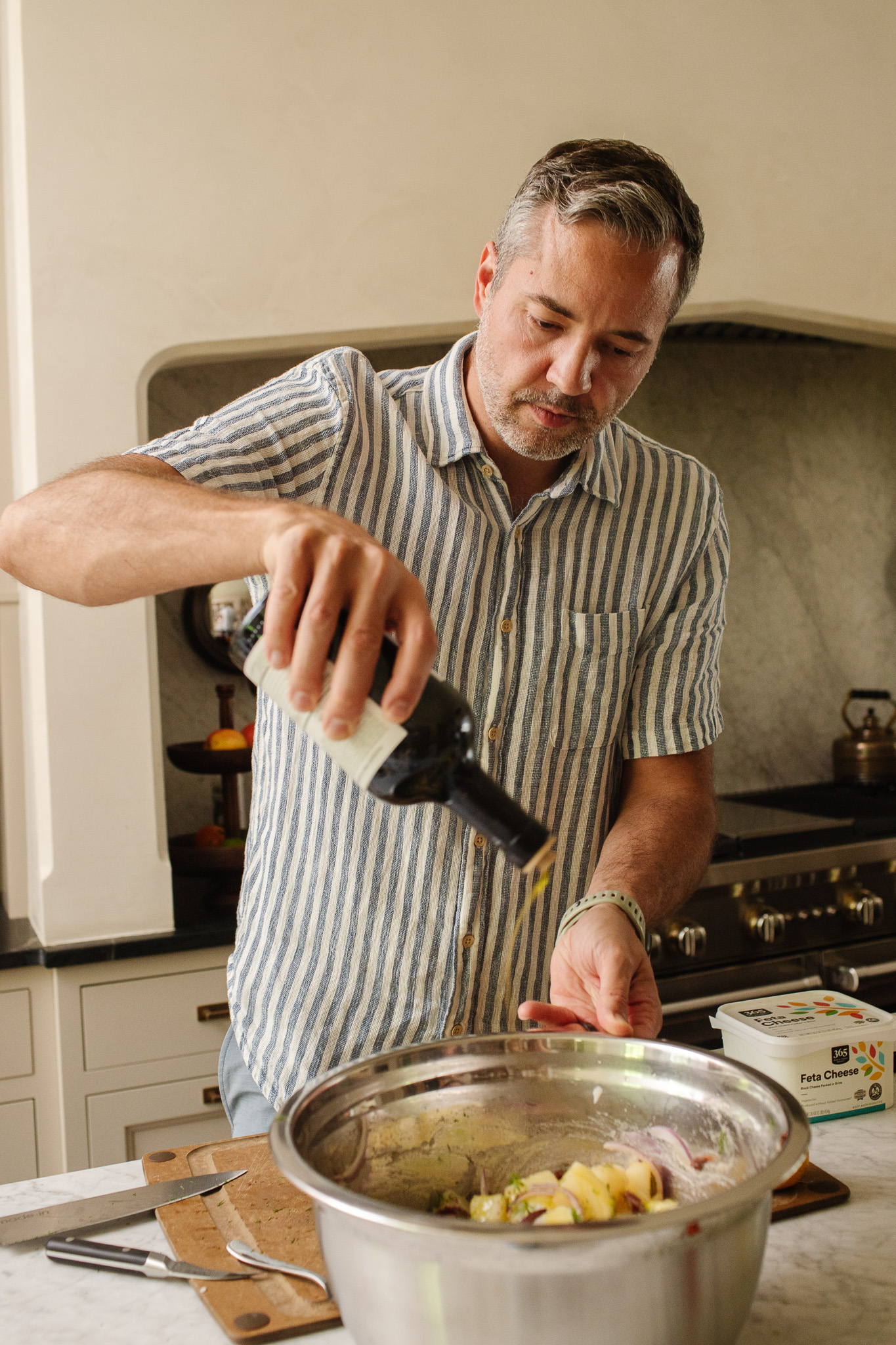 Chris pouring olive oil onto the Greek Potato Salad