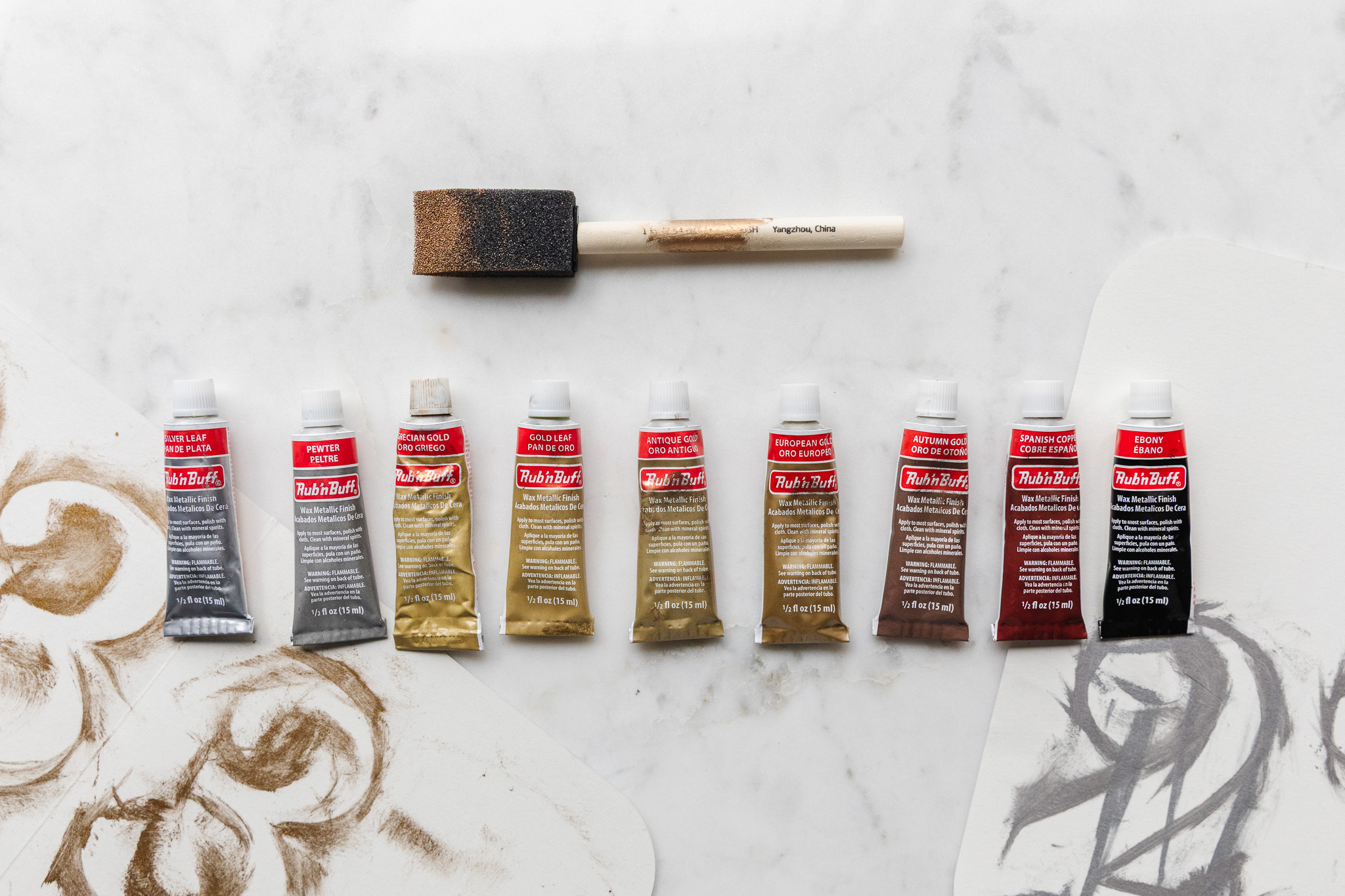All 9 Rub 'n Buff tubes in a line with a paint brush above
