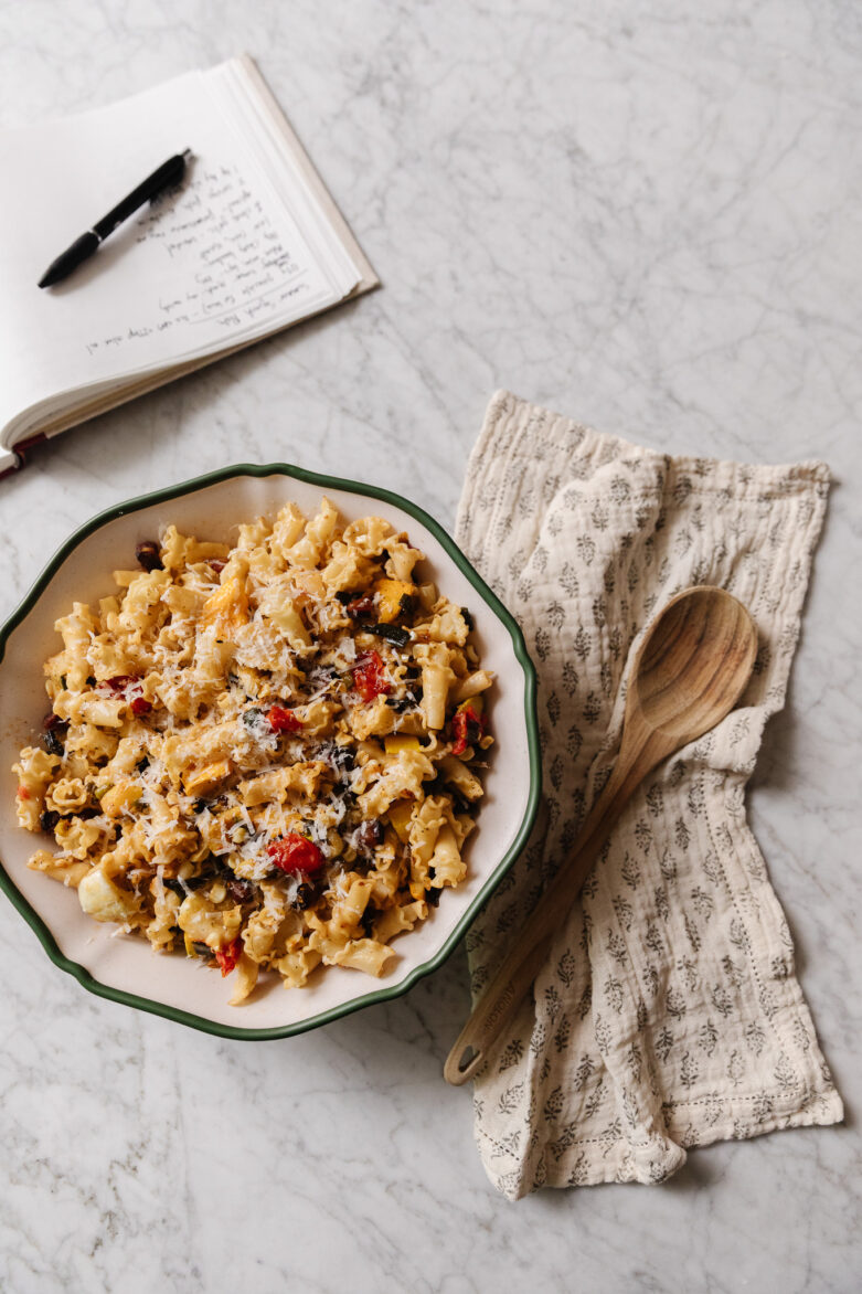 Summer squash pasta in a serving bowl next to a wooden spoon