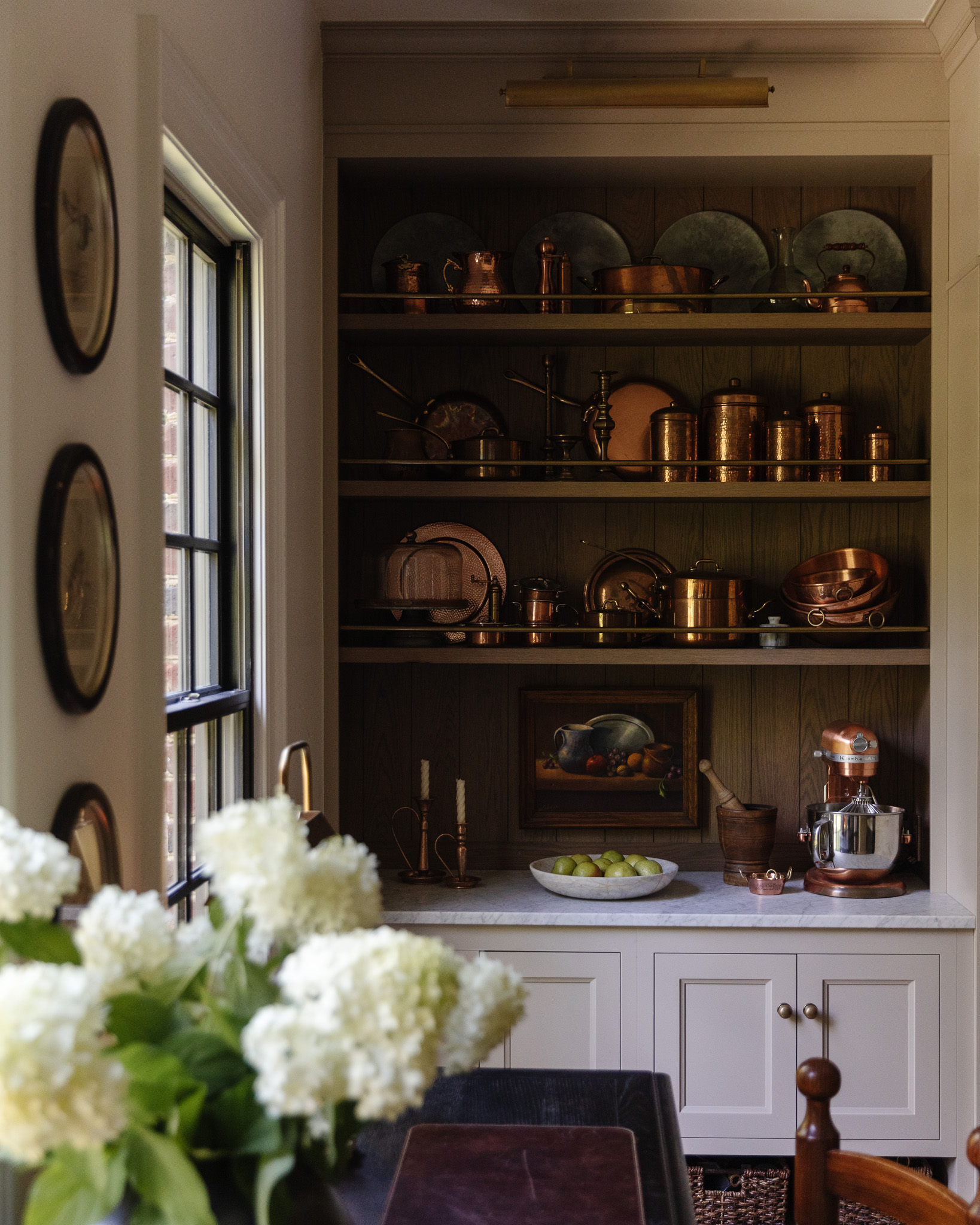 A collection of copper pans and pots on built-in kitchen shelves