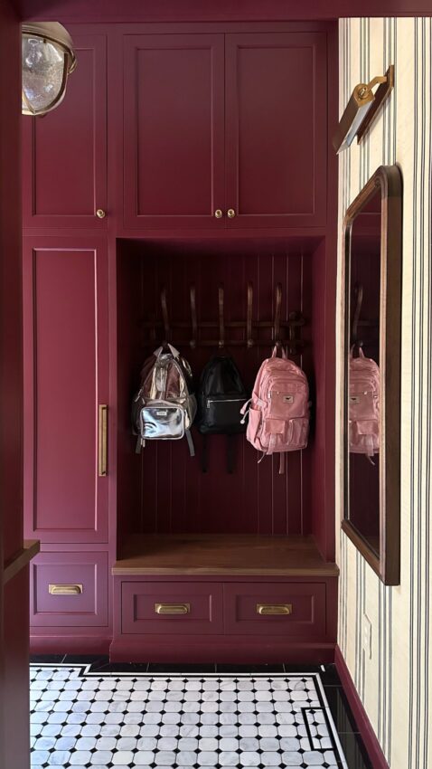 Two backpacks hanging up in the locker of the red mudroom