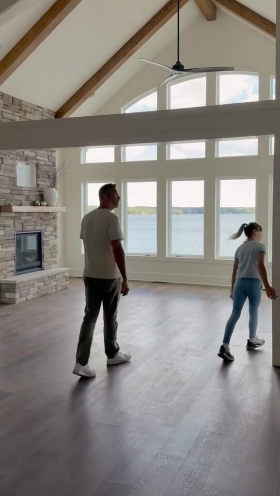 Empty living room in a lake house with a man and his daughter walking through
