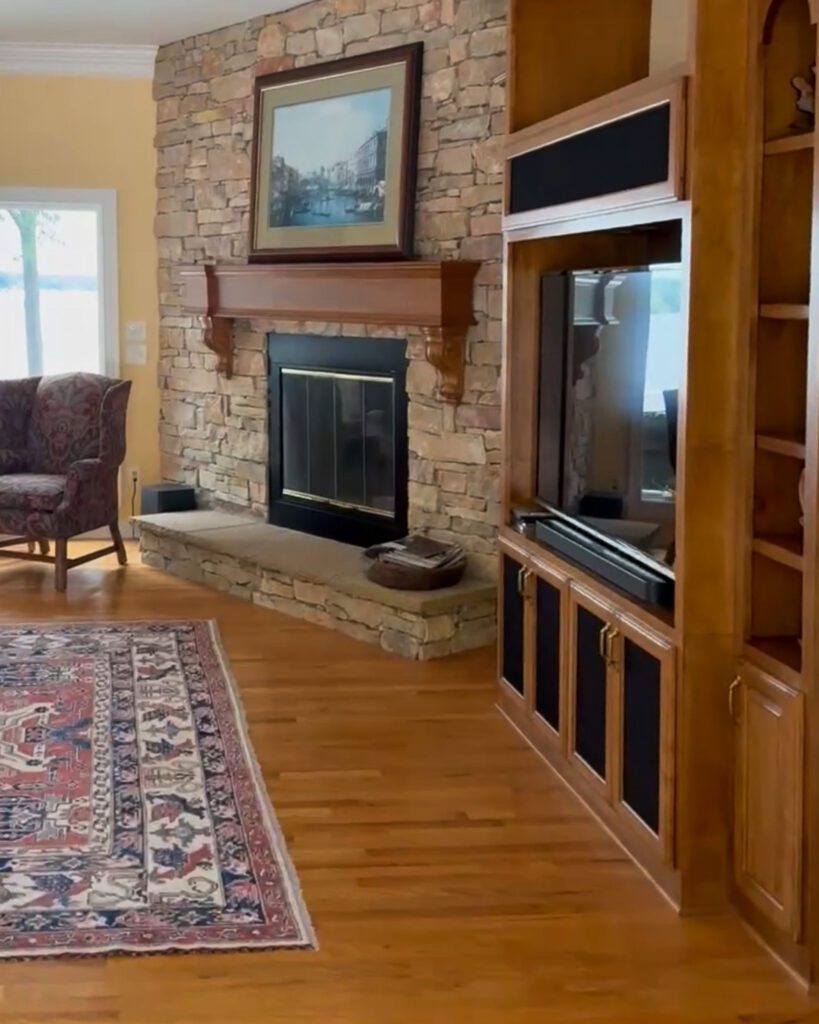 A stone fireplace next to a media console in a living room