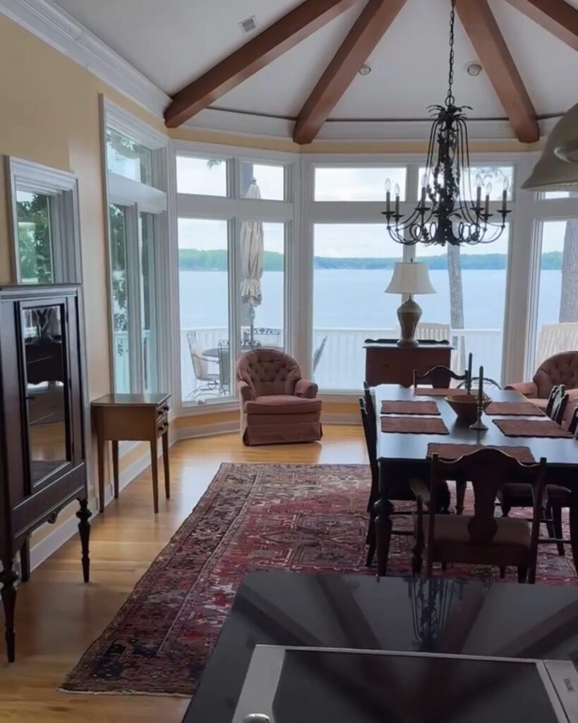 A beautiful angled dining room with beams on the ceiling and a view of the lake