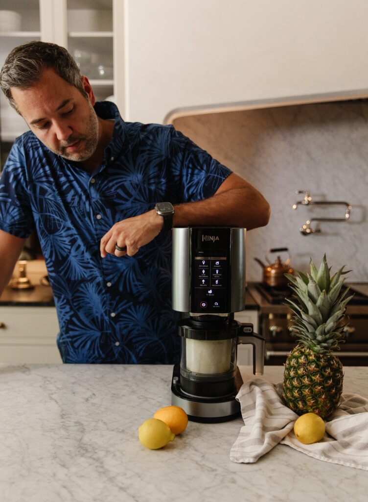 Chris next to a Ninja Creami with a pineapple, lemon, and