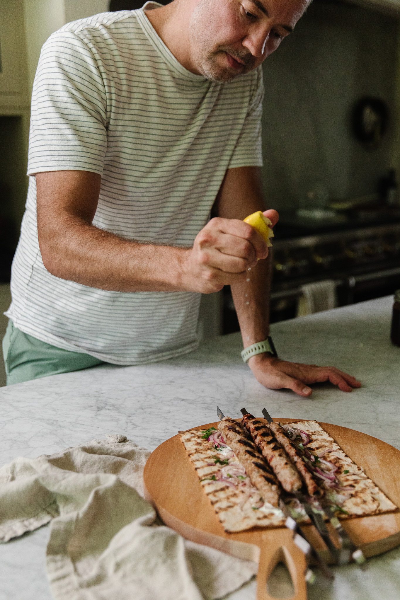 Chris squeezing lemon juice over the grilled pork kebabs
