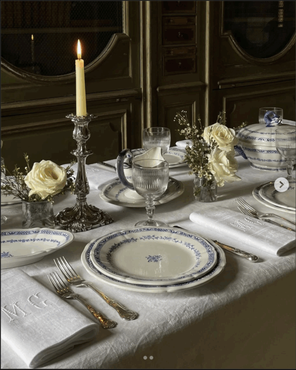 Beautiful table set with white linens, white candlesticks, polished candle holders, and monogrammed napkins