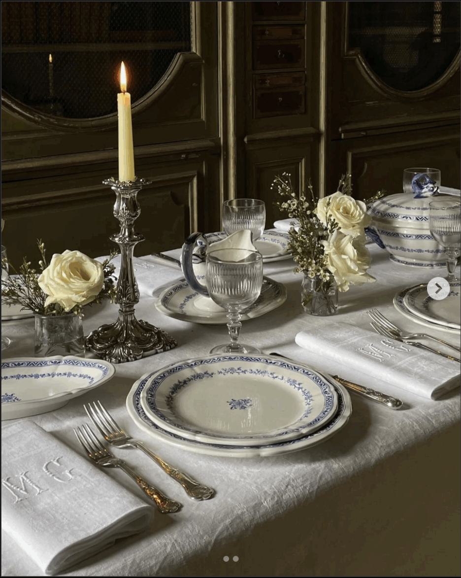 Beautiful table set with white linens, white candlesticks, polished candle holders, and monogrammed napkins