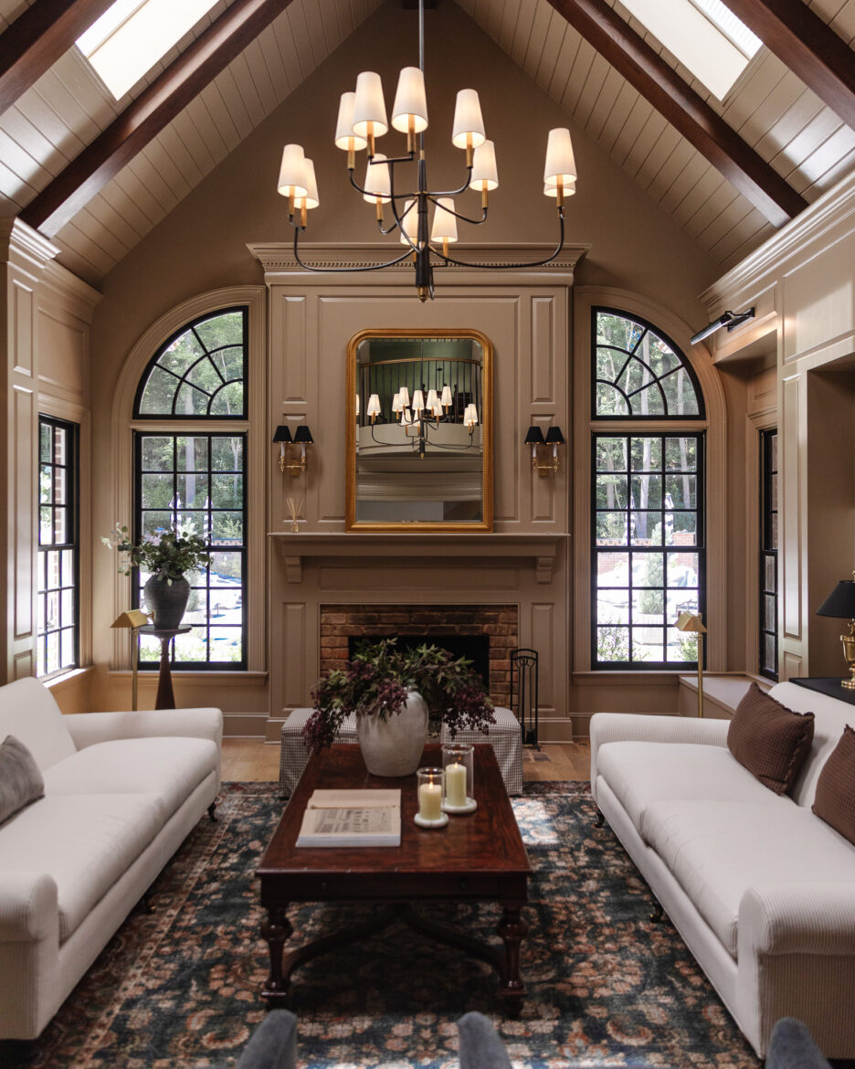 Moody modern traditional living room with navy blue vintage-style rug, two pinstripe sofas perpendicular to the fireplace.