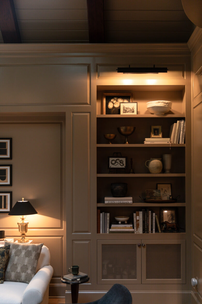 A built-in bookcase painted moody London Stone by Farrow & Ball with a picture light glowing overtop
