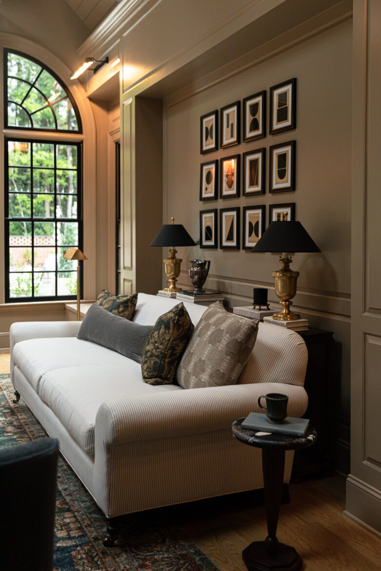 A sofa nook and small sofa table behind a Serena & Lily pinstripe sofa with a grid of 12 black and tan abstract pictures on the wall