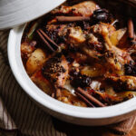 A white tagine pot filled with braised chicken and golden beets