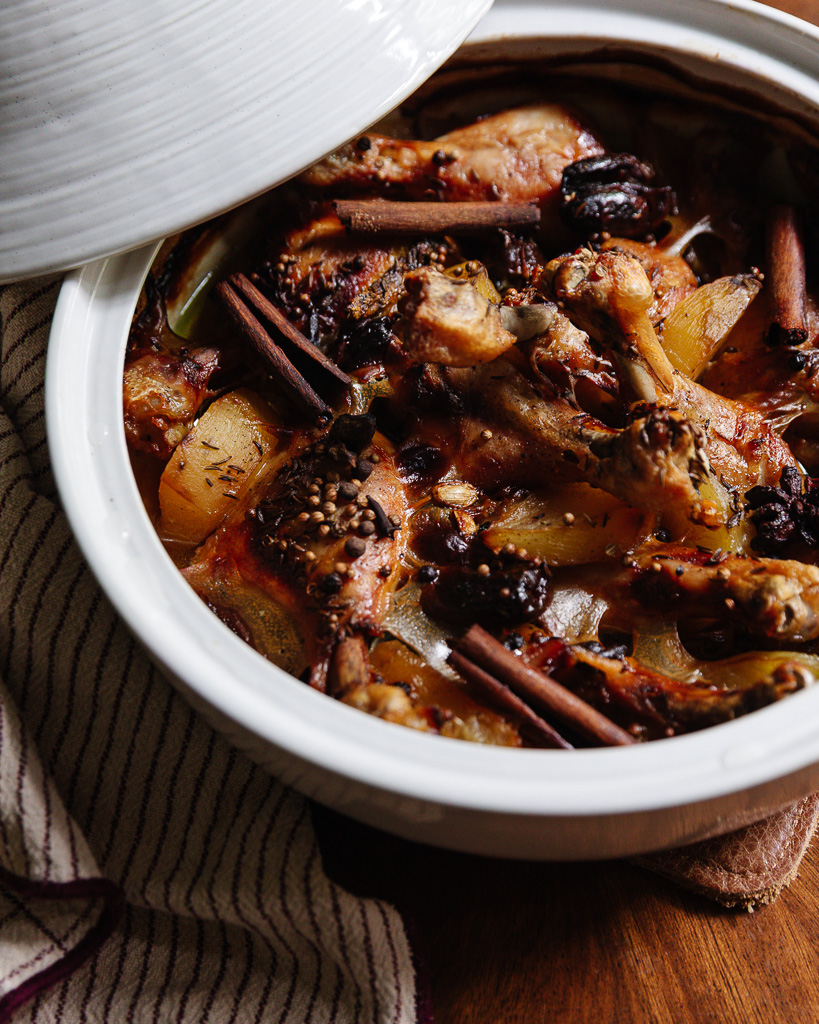 A white tagine pot filled with braised chicken and golden beets