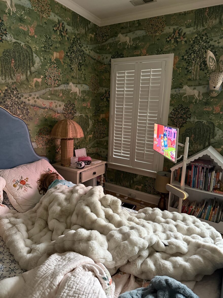 A child sick in bed watching Bluey on a portable TV