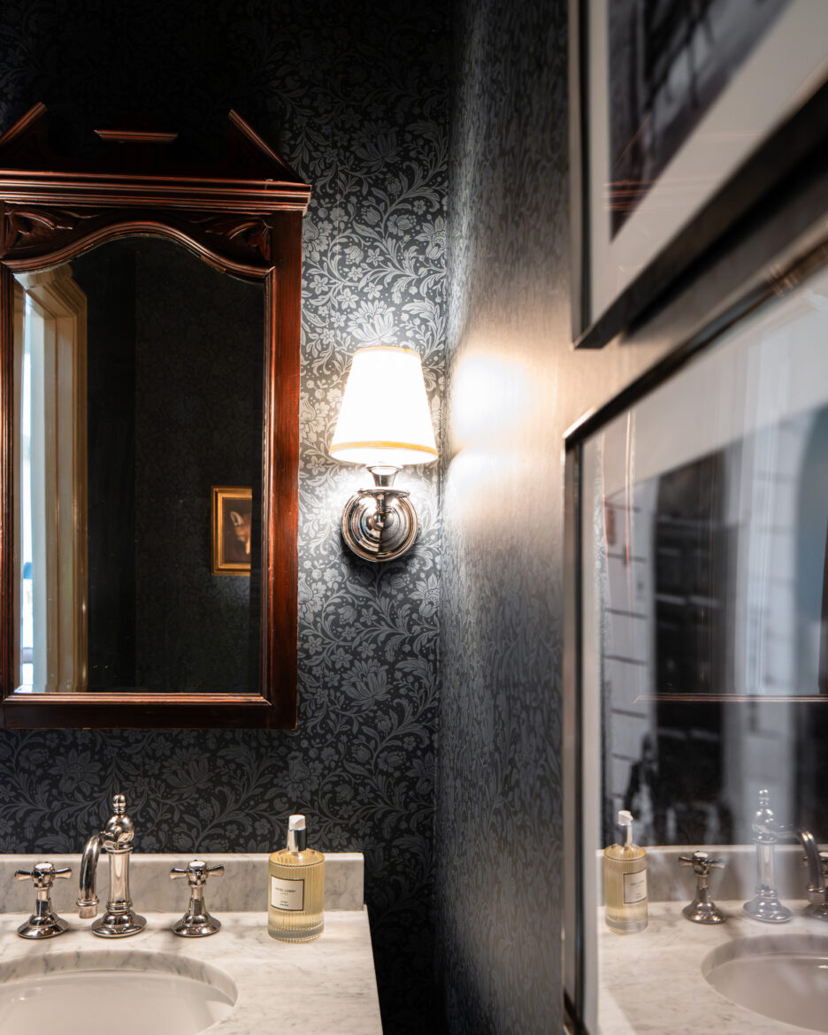 Powder bathroom with Hague navy wallpaper and two silver-framed black & white photographs