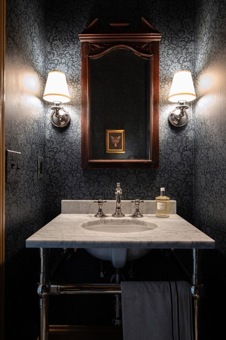 Powder bathroom with Hague navy wallpaper and sconces by the traditional-style mirror