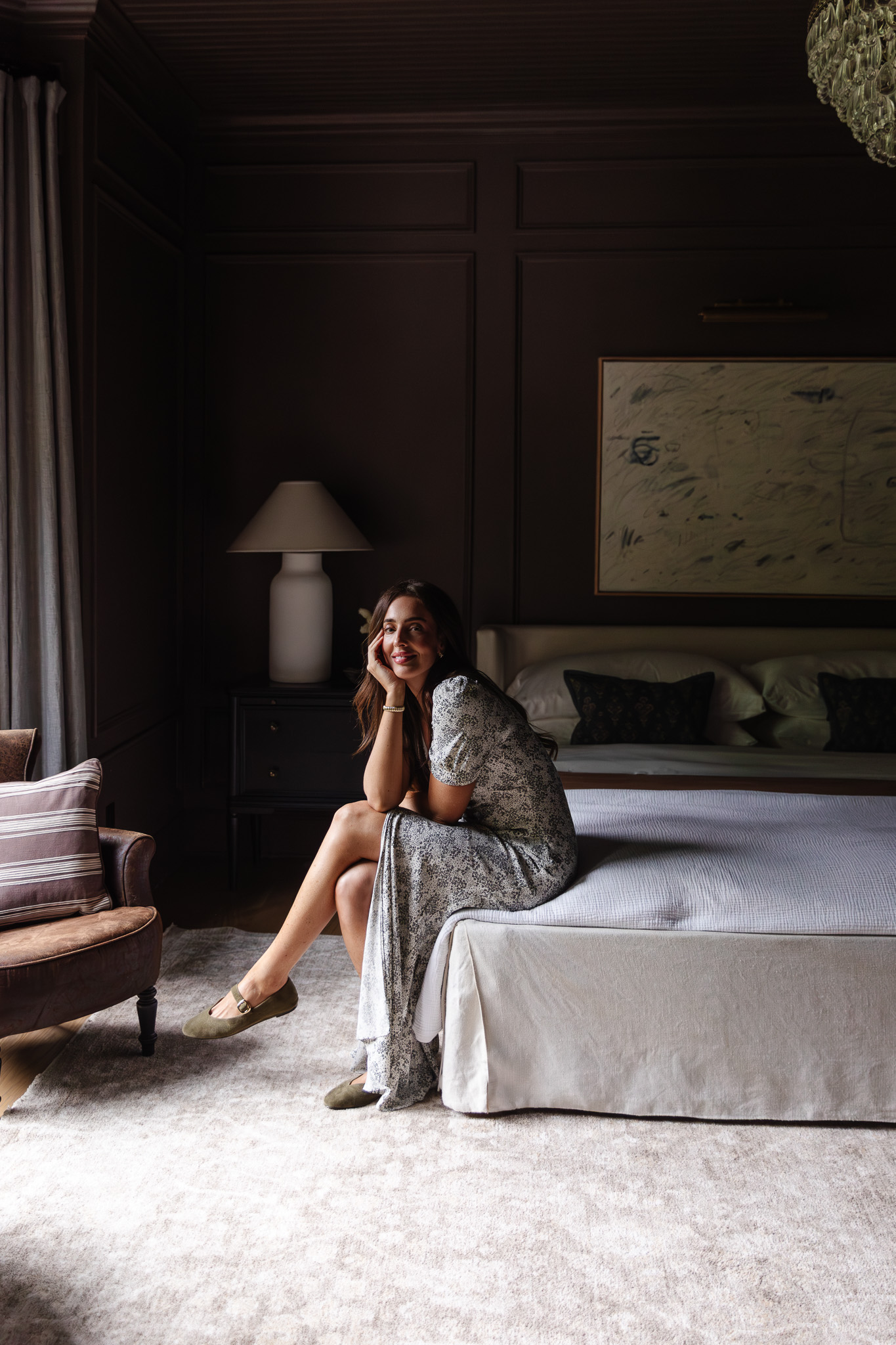 Julia sitting on the side of her bed with a neutral Palma rug underneath