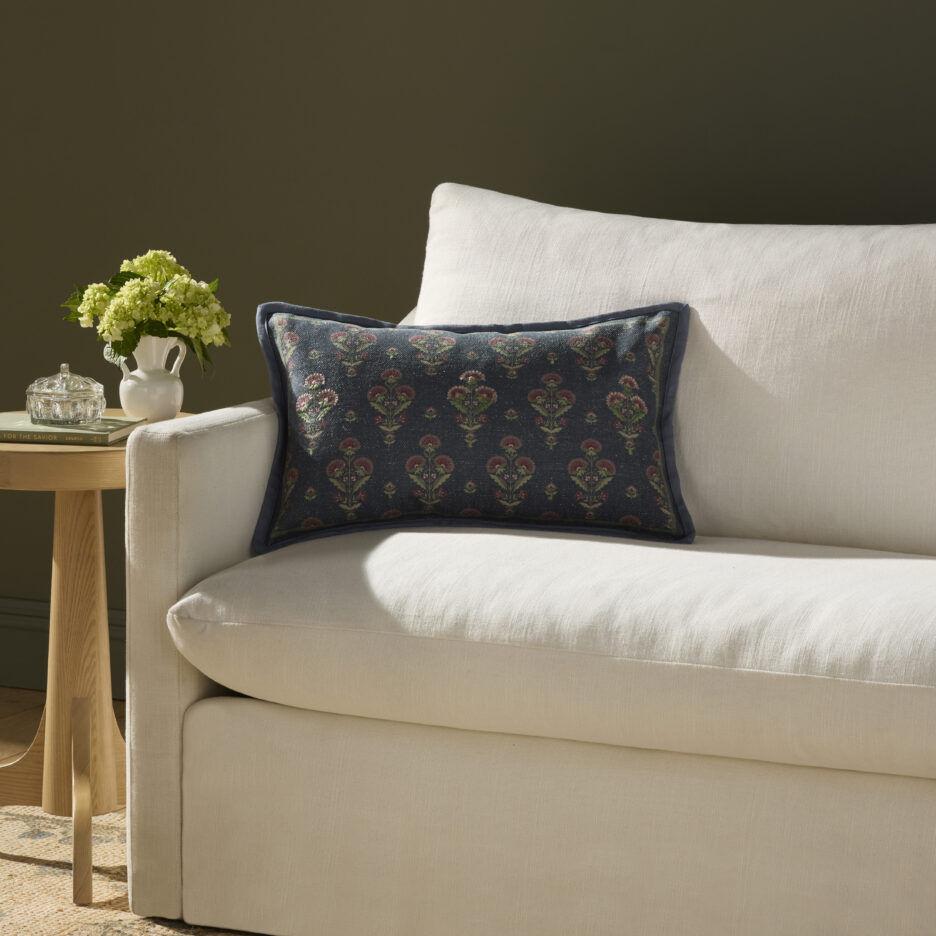A navy printed floral lumbar pillow on a white couch