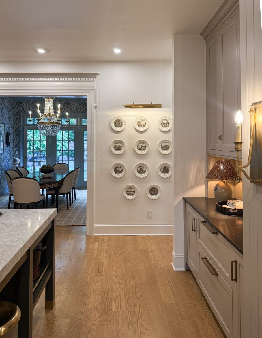 Plate wall in the kitchen with 11 plates in a grid under a picture light