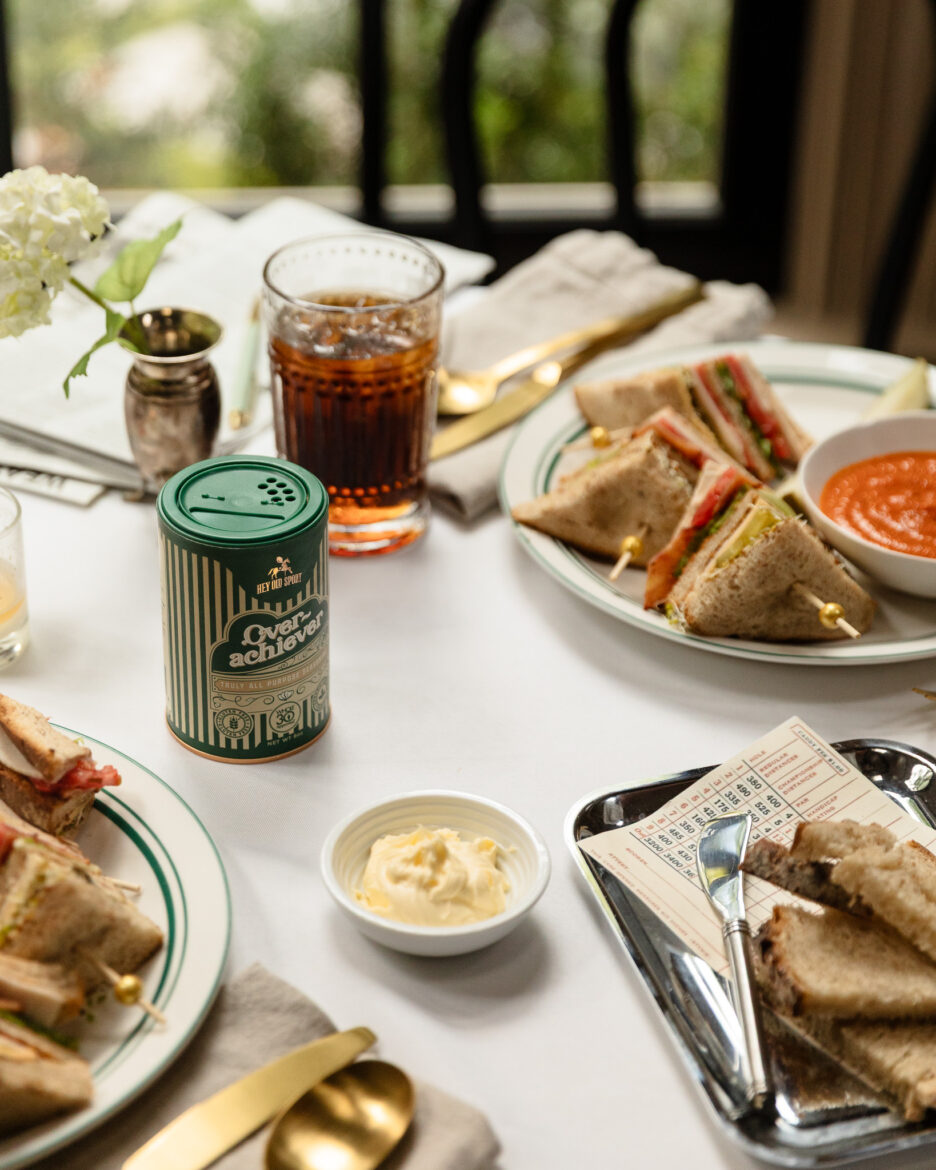 Snacks and sandwiches on a cozy dining table, perfect for a casual meal or brunch, featuring classic club sandwiches, dip, and beverages, styled for a home renovation or lifestyle blog.