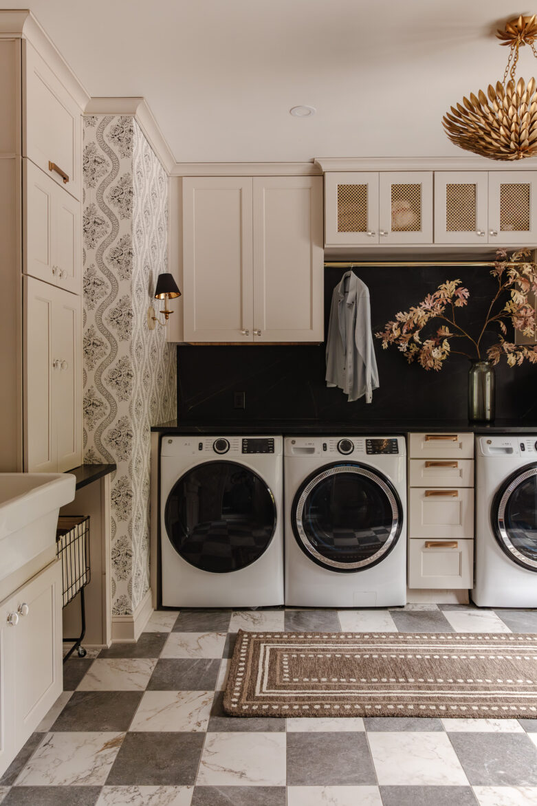 Chic laundry room with built-in cabinetry, black marble backsplash, and a decorative area rug, combining functionality and style for an elegant home space.