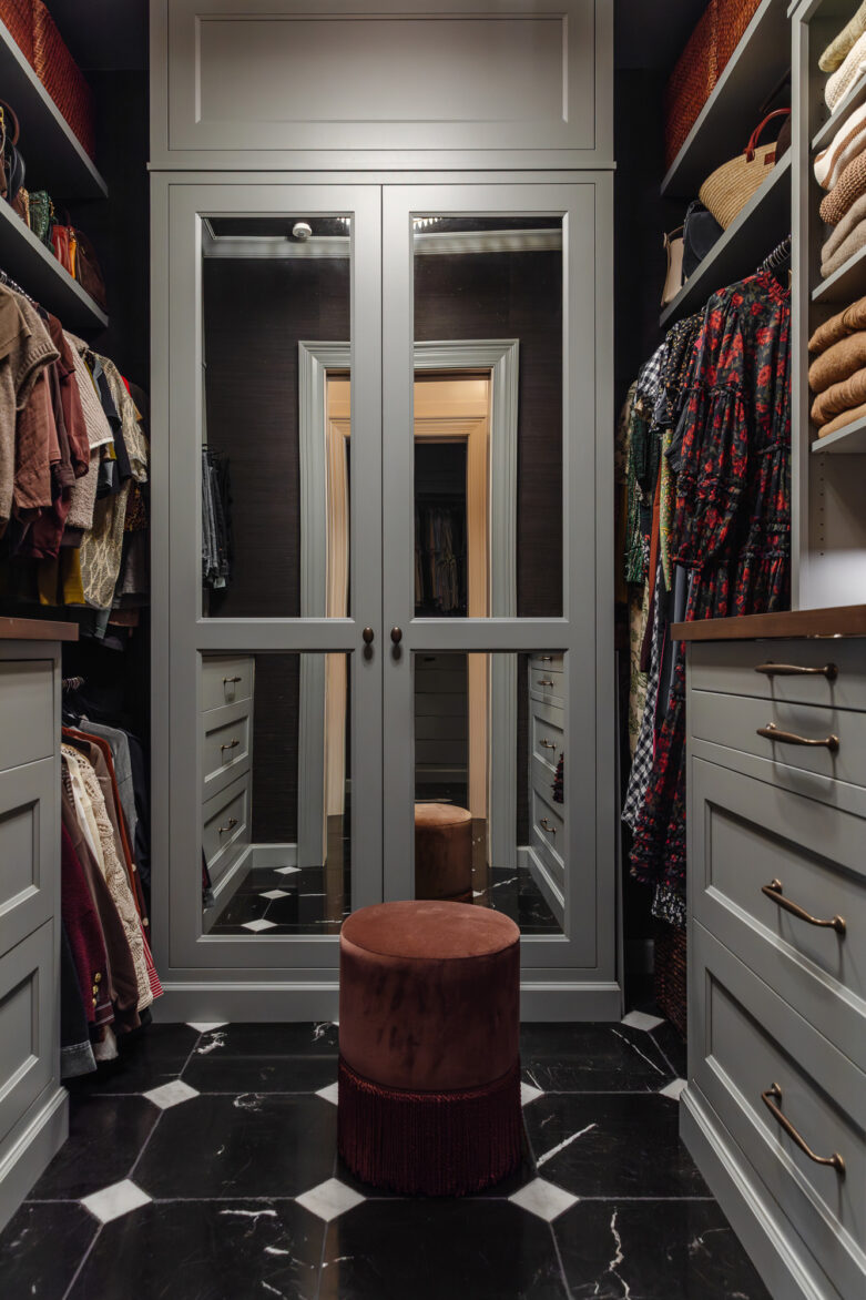 Luxury walk-in closet with custom cabinetry, and stylish organization, featuring dark clothing and accessories