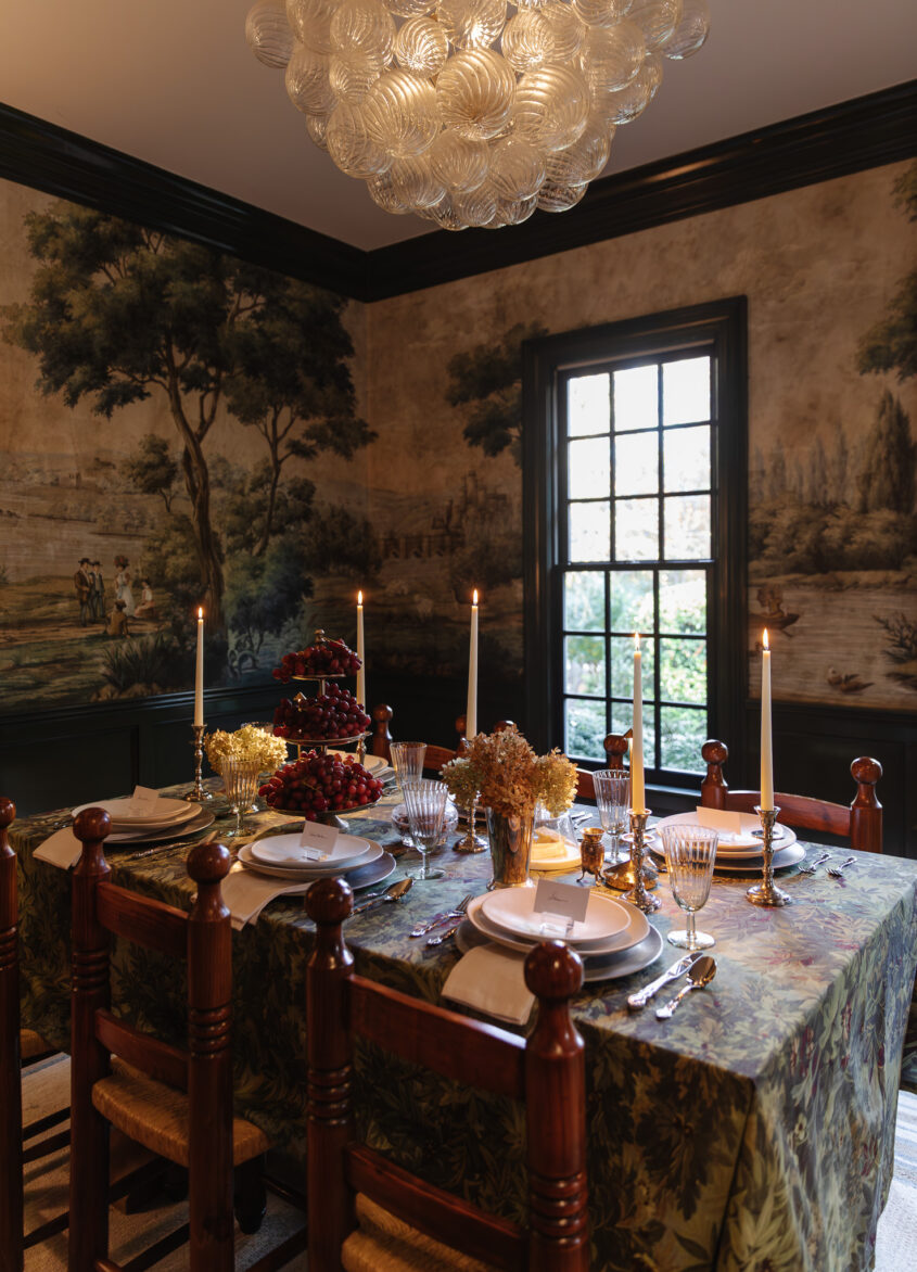 Lush, traditional dining room with elegant chandelier, rich wall mural, and vintage table setting, perfect for holiday gatherings and family dinners.