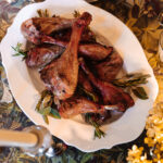 Succulent roasted turkey drumsticks on a beautifully set holiday dinner table with elegant tableware and festive decor.