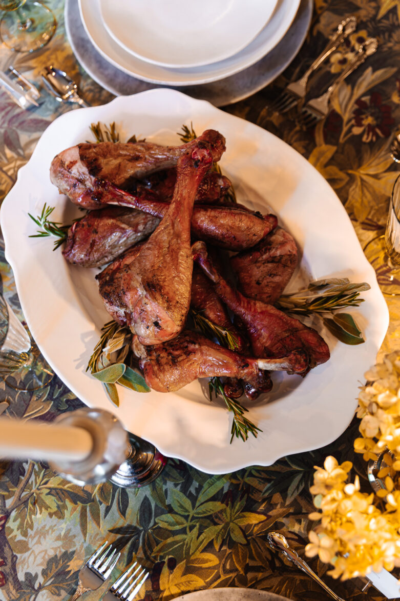 Succulent roasted turkey drumsticks on a beautifully set holiday dinner table with elegant tableware and festive decor.