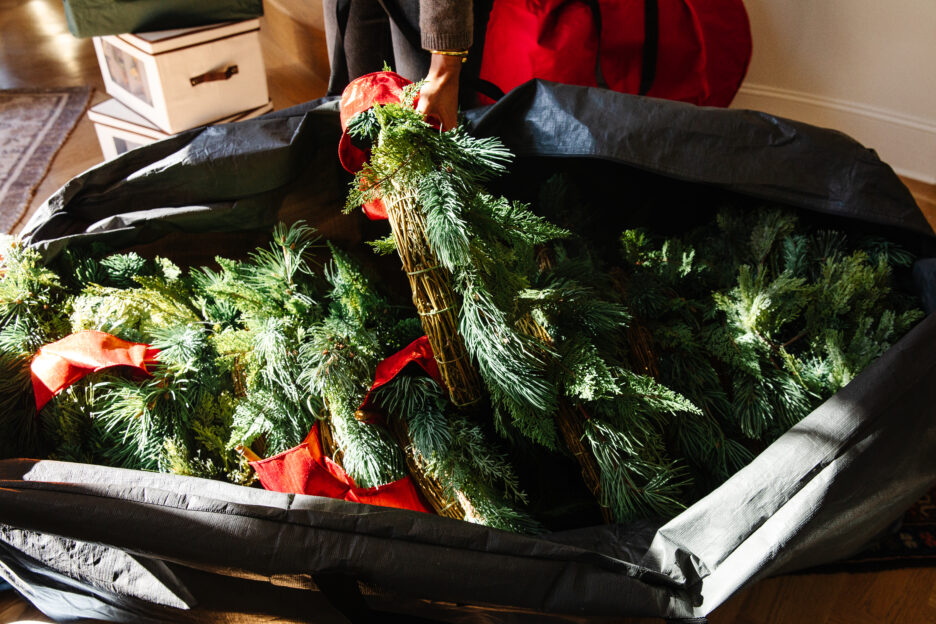 Freshly cut Christmas greenery with pine branches and red ribbons wrapped in a basket, ready for holiday decorating and Christmas crafts.