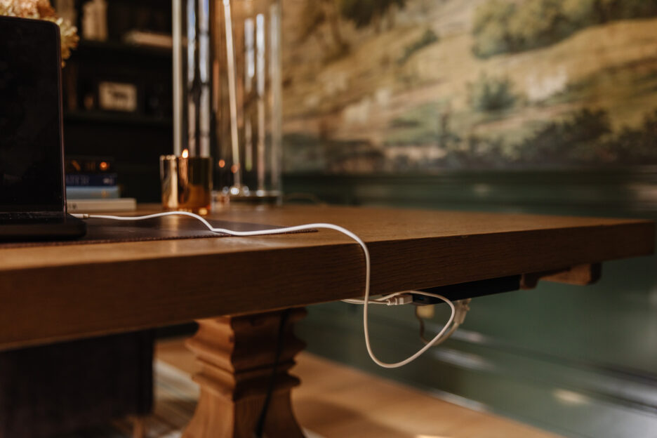 A laptop cable plugged into the desk-mounted power strip